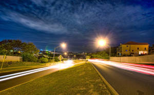 夜晚的道路，有汽車燈光軌跡和發光的路燈，在星空下。