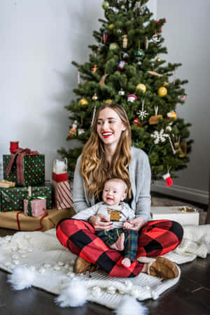 女性在裝飾好的聖誕樹附近抱著嬰兒。
