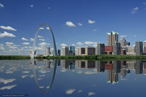 Gateway Arch 和城市天際線倒映在藍天下的平靜河面上。