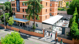 聖路易斯大學校園，學生在綠樹環繞的拱門附近行走。