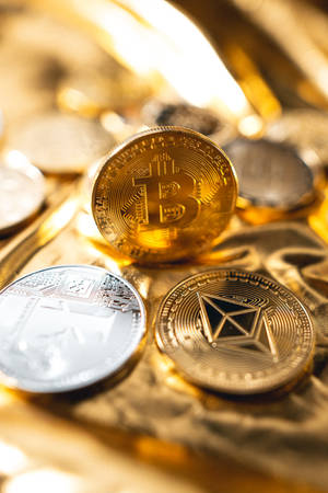 堆疊在金色布料上的比特幣和以太坊加密貨幣硬幣。