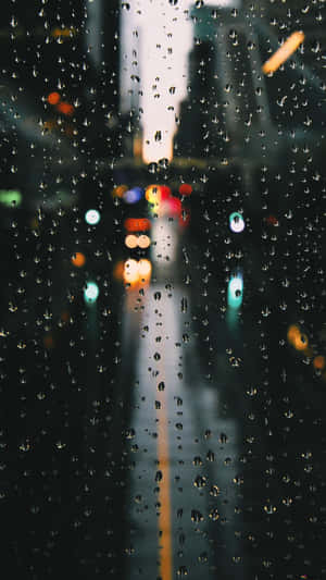 窗戶上的雨滴，模糊的城市燈光和夜晚發光的道路。