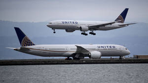 兩架聯合航空飛機，一架正在起飛，另一架在水邊滑行