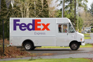白色FedEx送貨車停在潮濕的郊區街道上，有光禿禿的樹木。
