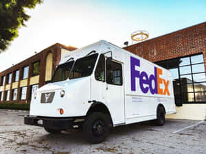 白色FedEx Ground送貨車停在磚砌建築前。