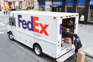 FedEx 送貨司機正在城市人行道上將包裹裝入一輛白色送貨車。
