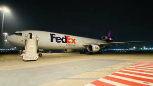 聯邦快遞貨機夜間停在機場停機坪，附有登機梯和跑道燈。