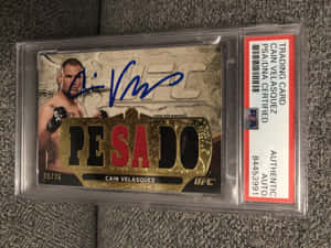 簽名UFC交易卡，Cain Velasquez，喺PSA認證保護殼入面，灰色表面。