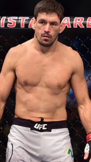 一位赤裸上身的男性MMA拳手穿著白色UFC短褲，在八角籠內。