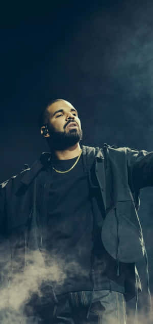 Drake 在舞台上表演，煙霧繚繞，燈光效果戲劇化。