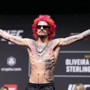 紅髮紋身的UFC拳手在台上自信地擺姿勢。
