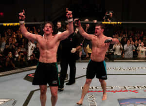 兩名筋疲力盡的MMA拳手在UFC八角籠內與歡呼的粉絲一起慶祝勝利。 — 冠軍 壁紙