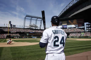 身穿白色球衣、印有 Griffey 名字和 24 號的棒球運動員在比賽中站在本壘板。