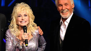 Dolly Parton 和 Kenny Rogers 在表演期間於舞台上微笑。