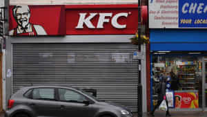 城市街道上關閉的KFC商店，帶金屬捲簾，附近有汽車和行人。