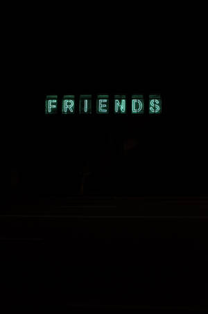 一個發光的綠色霓虹燈牌，在黑暗背景下顯示 FRIENDS。