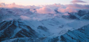 粉紅色和藍色黎明雲層下的雪山山脈