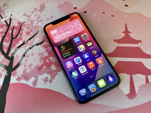 智能手機放在櫻花圖案表面，帶有寶塔和樹木設計。 — iPhone 14 壁紙