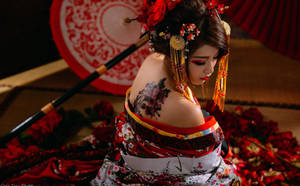 穿著紅白和服、帶有花卉紋身的藝妓，被紅色花瓣包圍。 — 日本 壁紙