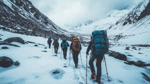 一群揹著背包和登山杖的遠足者在雪山中行走