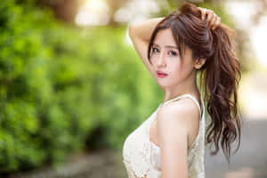 身穿白色蕾絲上衣的女性在戶外將手放在頭髮上擺姿勢。