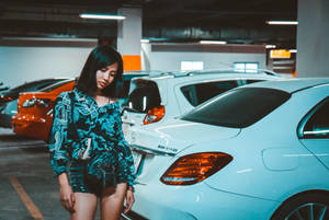 身穿圖案青綠色套裝的女性站在地下停車場白色Mercedes AMG旁。 — 汽車 壁紙