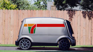帶有7-Eleven標誌的銀色自動送貨車停在木柵欄附近。 — Vans GIF 壁紙