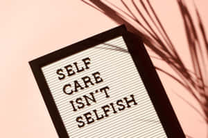 字母板顯示 self care isn't selfish，粉紅牆上有棕櫚葉影子
