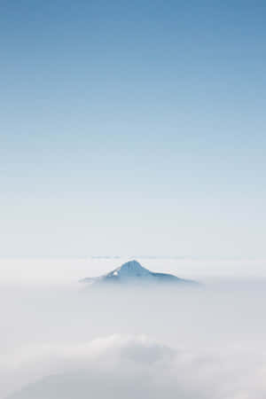 在清澈藍天下，從雲海中浮現的雪山頂峰。