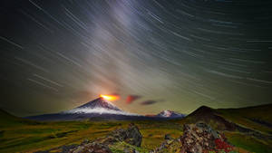 夜晚火山爆發，上方有星軌