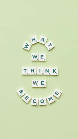 Scrabble 字母牌排列在綠色背景上拼出「What we think we become」。
