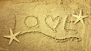沙中畫出的 love 字樣，旁邊有兩條海星。