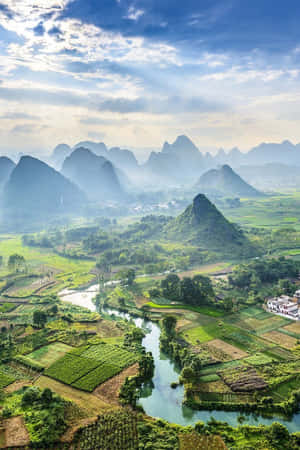 在藍天下，一條河流流經綠色稻田，背景是喀斯特山脈。