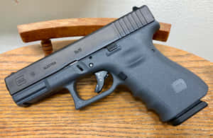 木桌上的黑色Glock 19手槍，帶有可見標記和紋理握把。 — Glock GIF 壁紙