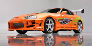 橙色豐田Supra，帶有賽車貼紙和後翼，在反射地板上。