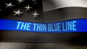 黑色旗幟，帶有銀色星星和藍色條紋，上面寫著「THE THIN BLUE LINE」，向警察致敬。