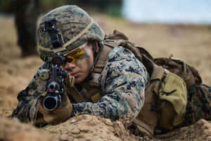 穿著迷彩裝備的士兵在泥地上以俯臥姿勢瞄準步槍。