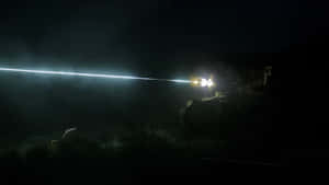 軍用車輛在沙漠夜間發射明亮的激光束。