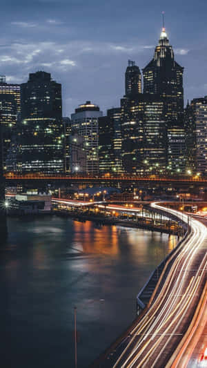 黃昏時分的城市天際線，燈火通明的建築物和移動車輛的光跡。