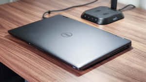 合上的銀色 Dell 筆記型電腦放在木桌上，附近有無線路由器。