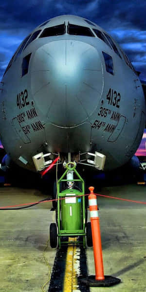 軍用運輸機機頭，帶有維修設備和橙色錐體，在暮色中的停機坪上。 — Pixel 3 壁紙