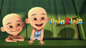 兩個動畫光頭男孩在帶有Upin & Ipin標誌的綠色木柵欄後面微笑。