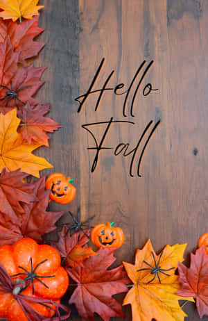 秋葉和南瓜，木頭上有蜘蛛，帶有'Hello Fall'文字。