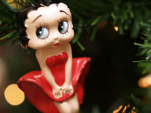 穿著紅色連衣裙的 Betty Boop 裝飾品掛在聖誕樹上，帶有燈光。