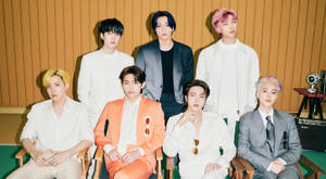 七位K-pop偶像穿著時尚西裝，頭髮色彩繽紛，在攝影棚內擺姿勢。