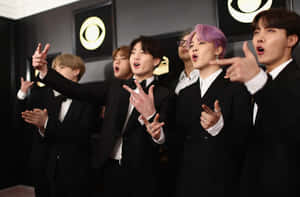 BTS 成員身穿黑色燕尾服在格林美獎頒獎典禮上充滿活力地擺姿勢。