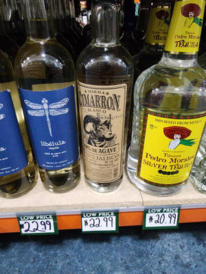 商店貨架上的一排龍舌蘭酒瓶，附有低價標籤。