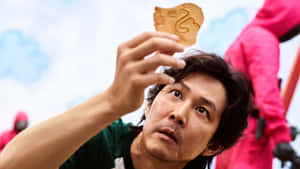 男子手持木製魷魚代幣，水滴從下巴滴落戶外。