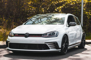 白色 Volkswagen Golf GTI 在陽光明媚的日子停放在戶外。