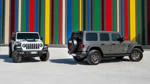 兩輛Jeep Wranglers停在混凝土表面上的彩色條紋牆前。